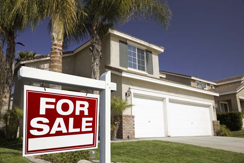 For sale sign in front of a house seen before scheduling home inspection services