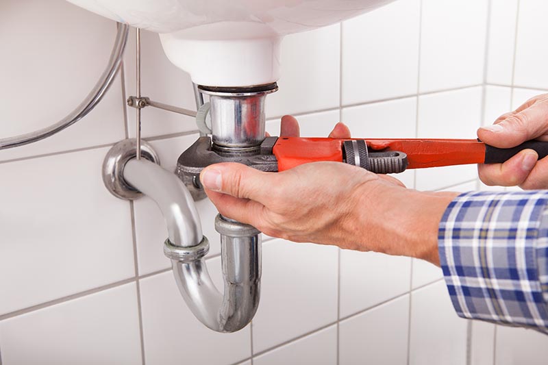 Plumber fixing a sink pipe before home inspection services are scheduled 